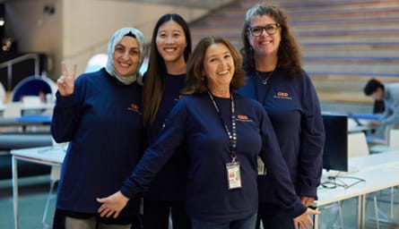 Four engineers pose for a photo at the Intuit campus wearing dark blue shirts with the GED logo.